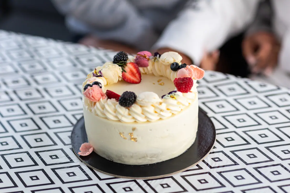 A cream cake dressed with berries and flowers, on the patterned cockpit table.