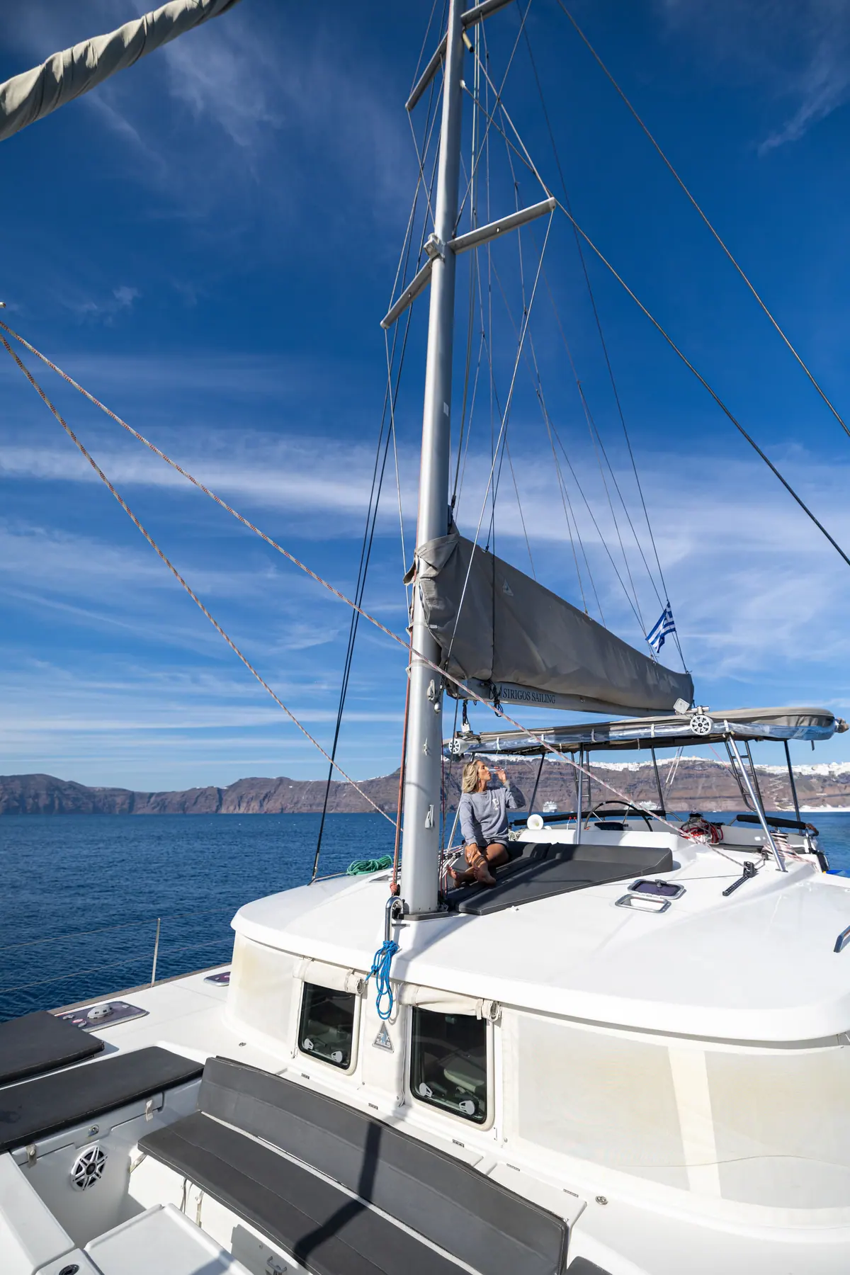 The catamaran under sail with guests forward on the trampolines.