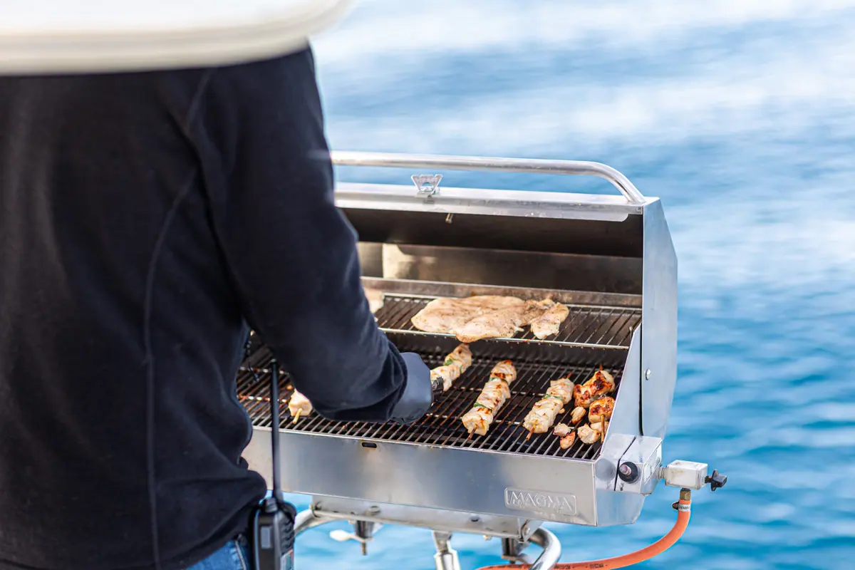 Skewers and chicken on the stern grill, open blue water beyond.