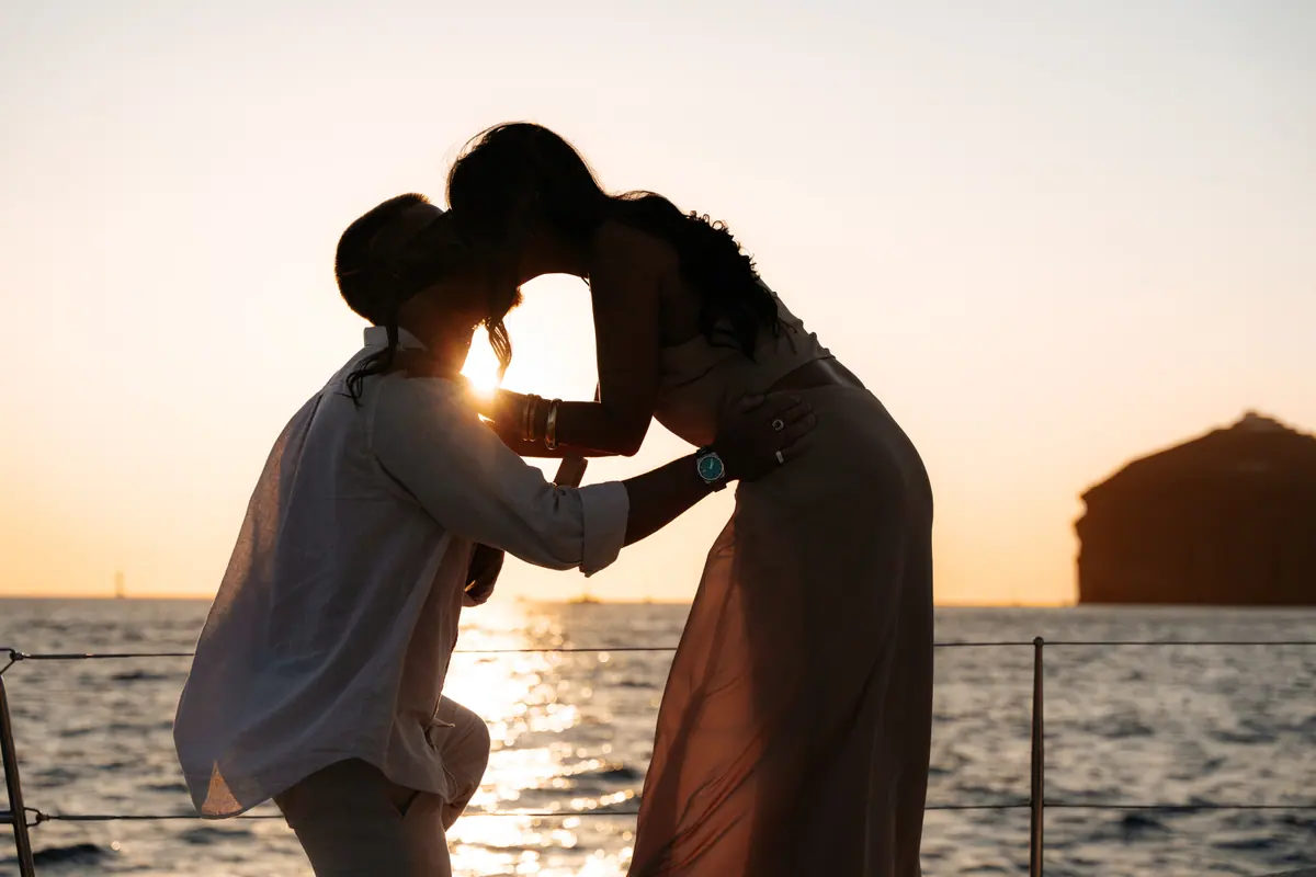 A couple kissing at the bow, silhouetted against the low sun.