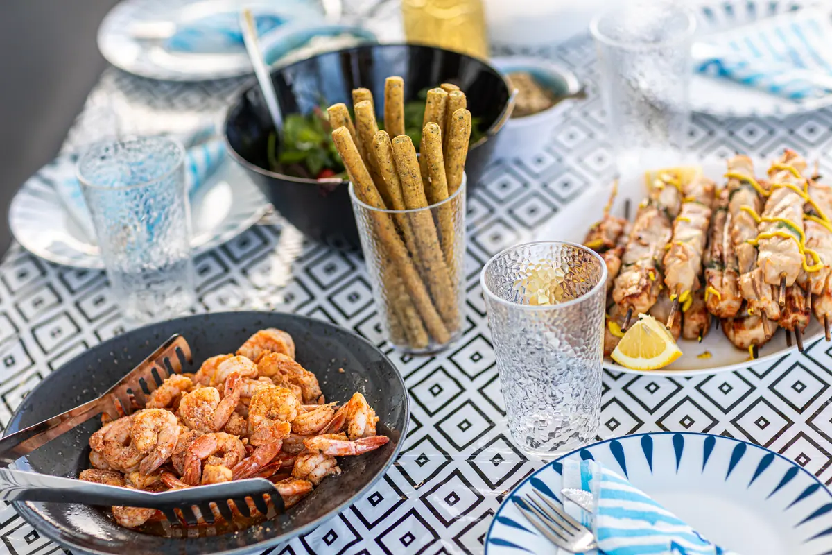 Crevettes grillées, gressins et verres posés sur la table à motifs du cockpit.