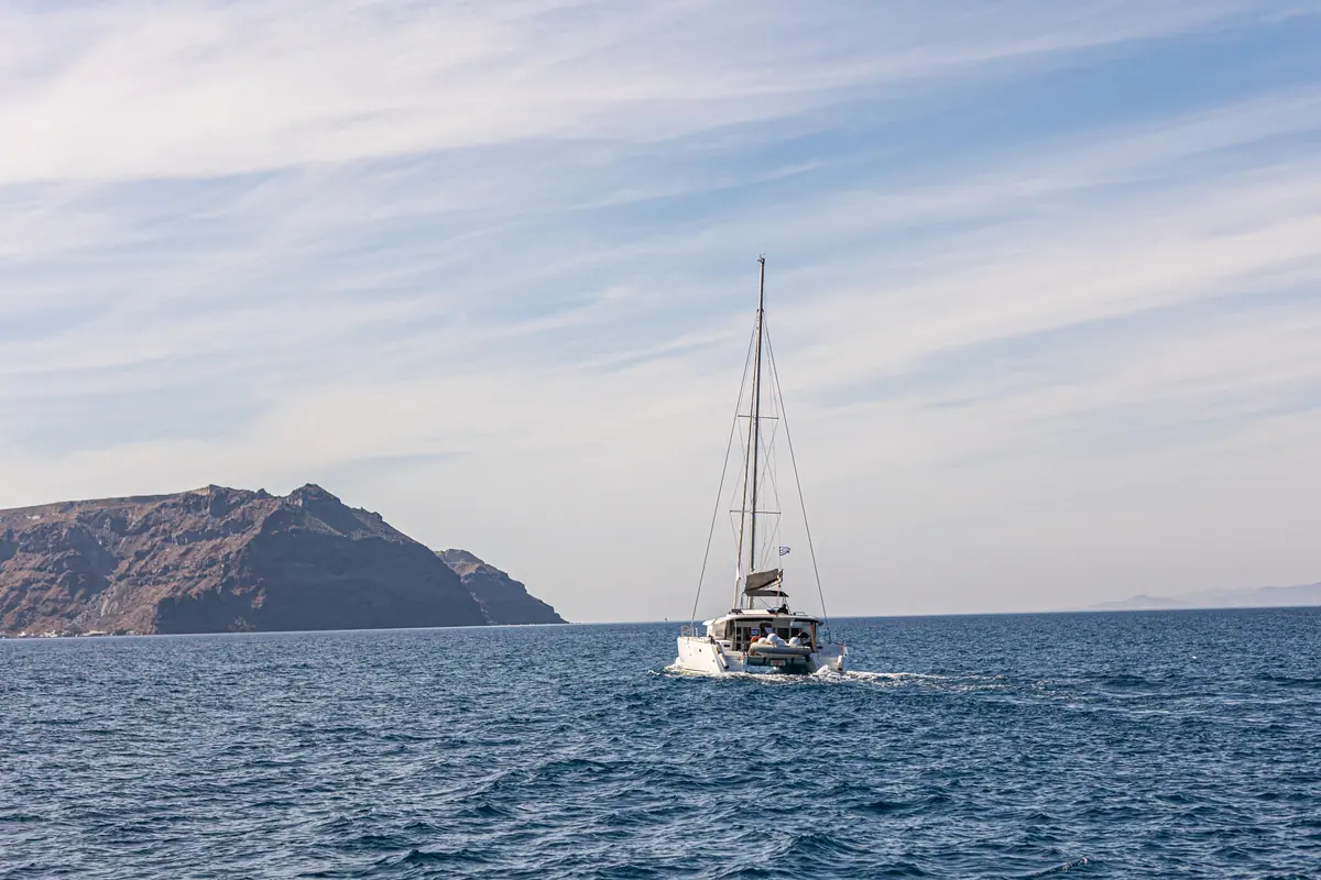 Under way past the low islet, the caldera opening out beyond it.