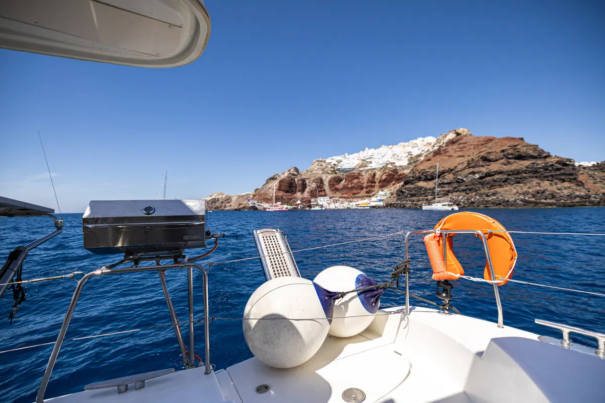 Ammoudi below and the white houses of Oia above it, seen over the stern rail.