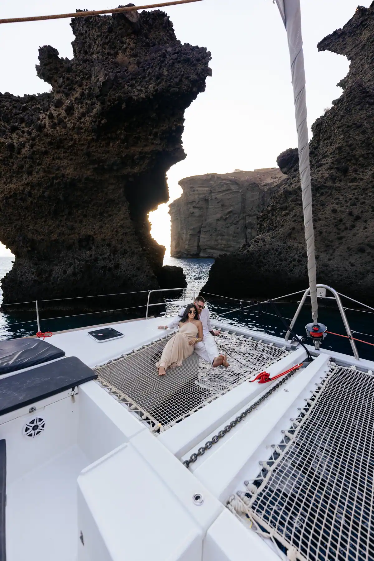 The pale pumice wall close aboard, with the boat’s foredeck in the foreground.