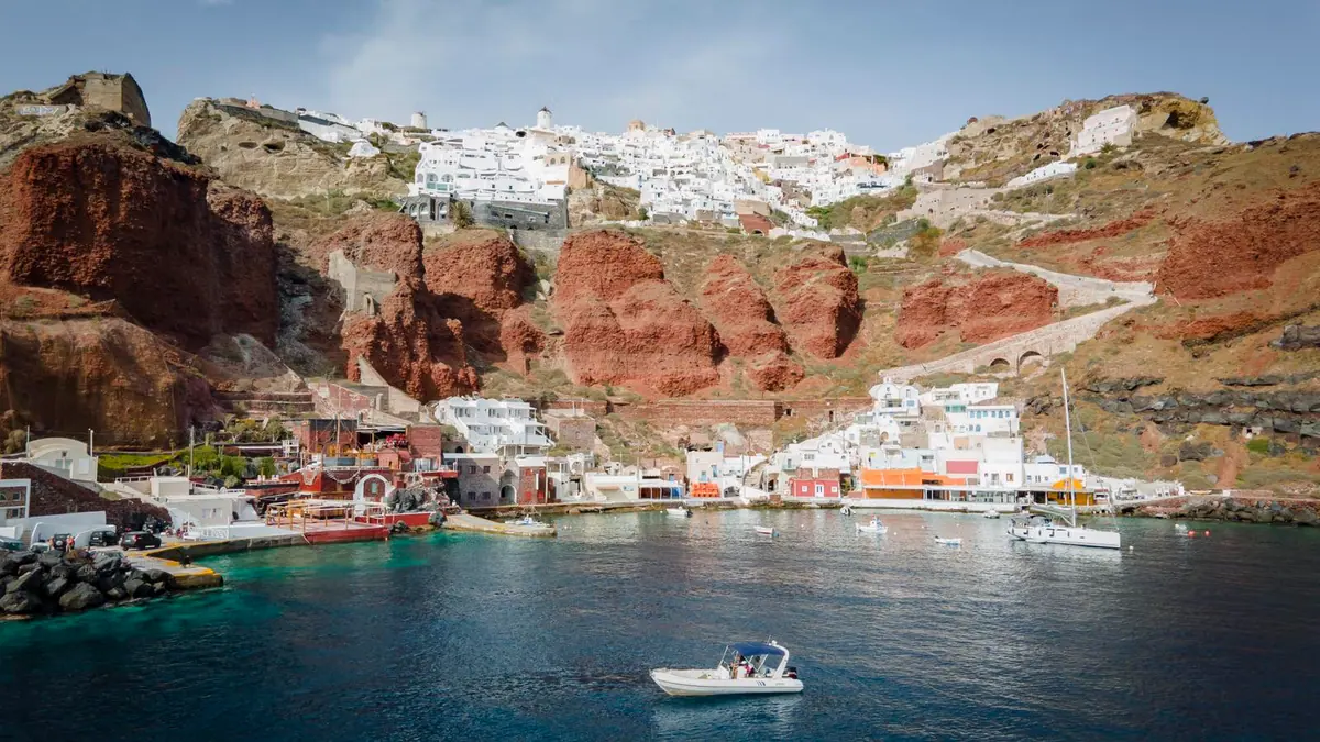 La baie d’Ammoudi depuis la mer : les tavernes au pied de la falaise, Oia sur la crête au-dessus.